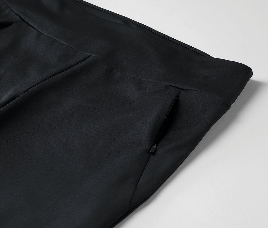 Detail černých kalhot s kapsou na zip.