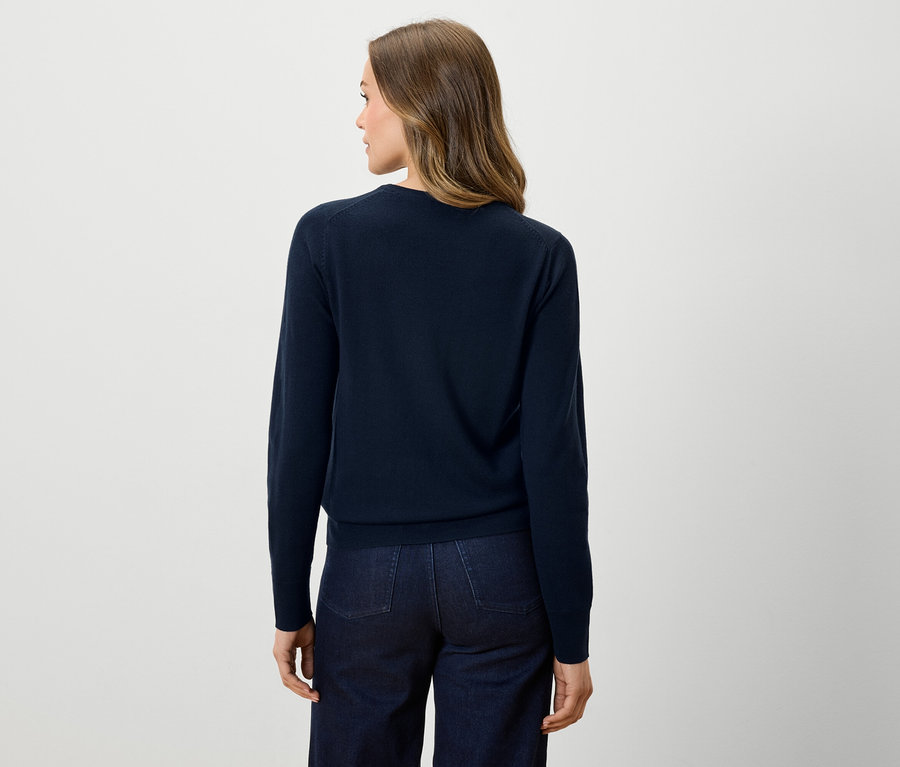 Zezadu je vidět žena v tmavě modrém svetru a tmavých džínách.