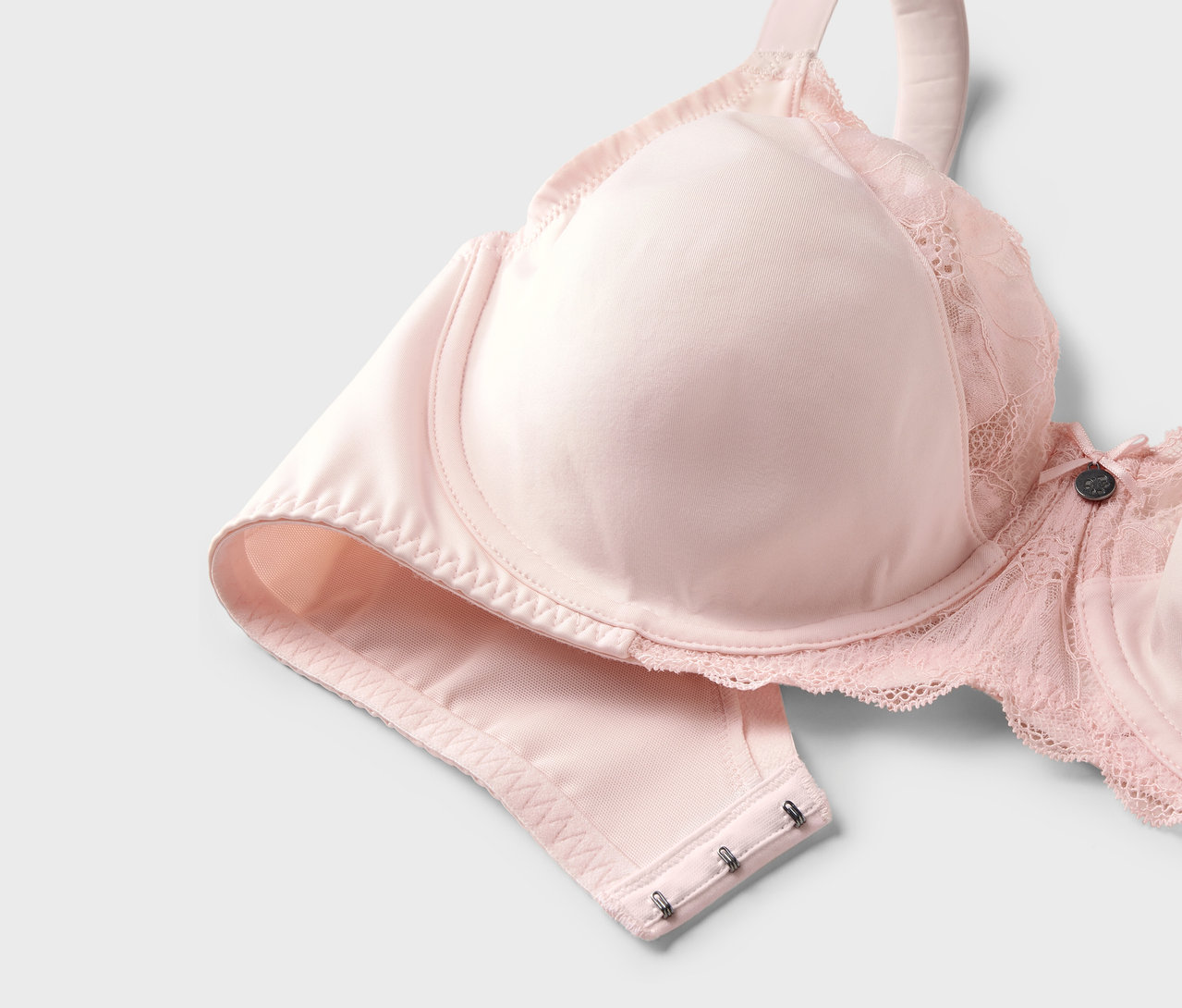 Světle růžová zmenšující podprsenka s krajkovými detaily.