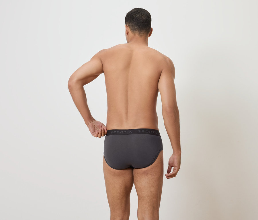 Muž zády k fotoaparátu, má na sobě šedé slipy.