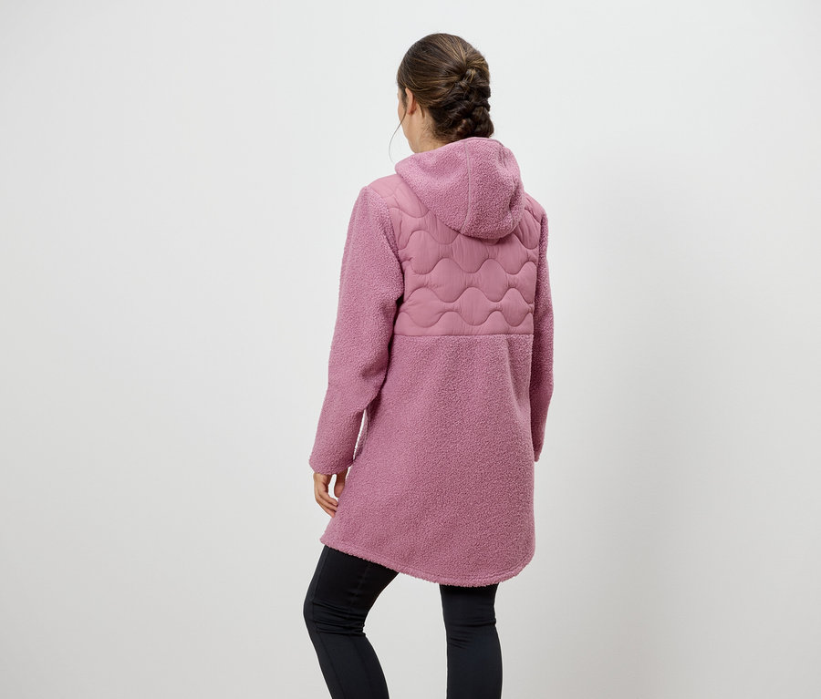 Žena zády ke kameře má na sobě růžový kabát s kapucí a černé legíny.