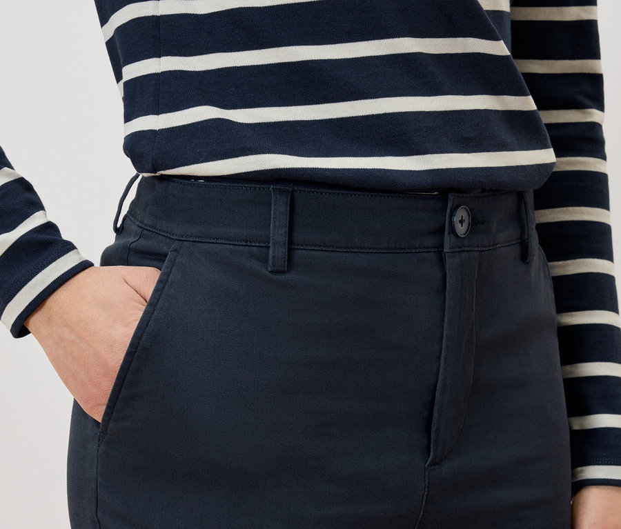 Detail osoby s rukou v kapse kalhot a v pruhovaném tričku.