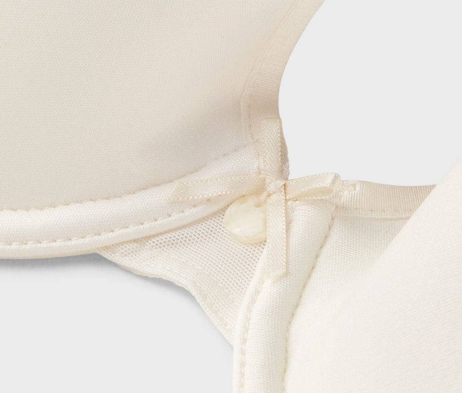 Detailní pohled na krémovou podprsenku s mašličkou.