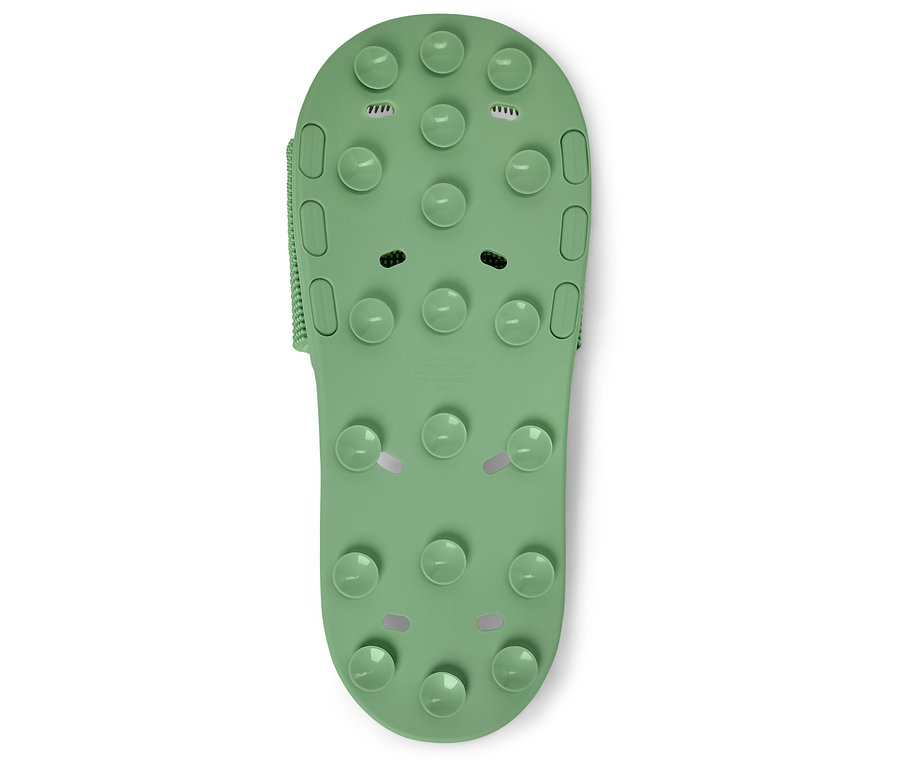 Detail jednoho zeleného koupelnového pantofle s výstupky na bílém pozadí.