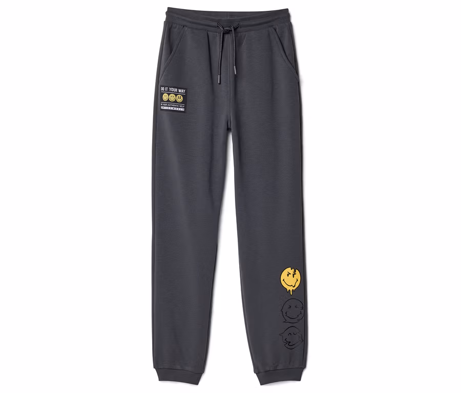 Tmavě šedé dětské joggingové kalhoty SMILEYWORLD® se stahovací šňůrkou, nášivkou "DO IT YOUR WAY" a třemi tajícími smajlíky na pravé nohavici.