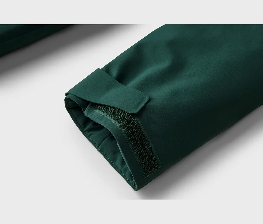Detail tmavě zeleného rukávu s nastavitelnou manžetou a zapínáním na suchý zip.