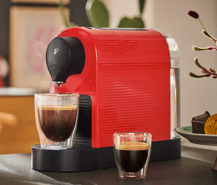 Červený kávovar Cafissimo pure+ s dvěma šálky kávy.