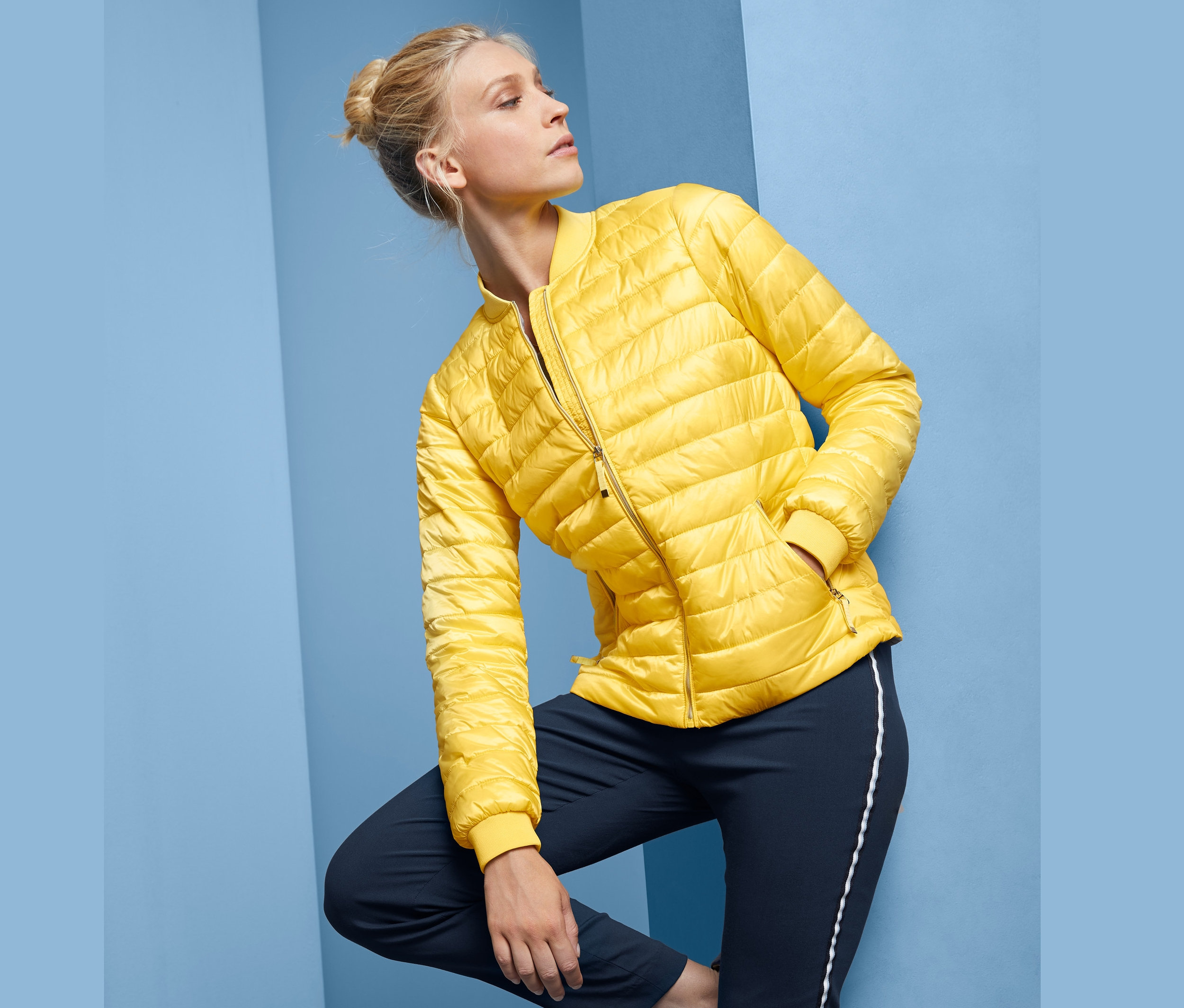 Blondýna pózuje v žluté prošívané bundě.