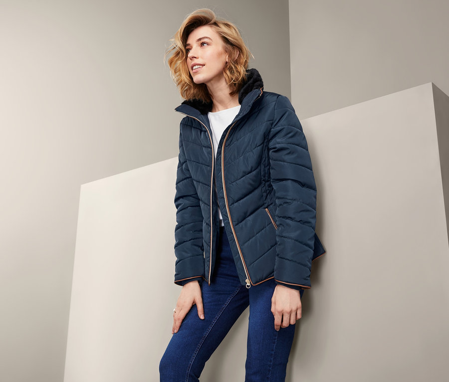 Blondýna pózuje v modré prošívané bundě.