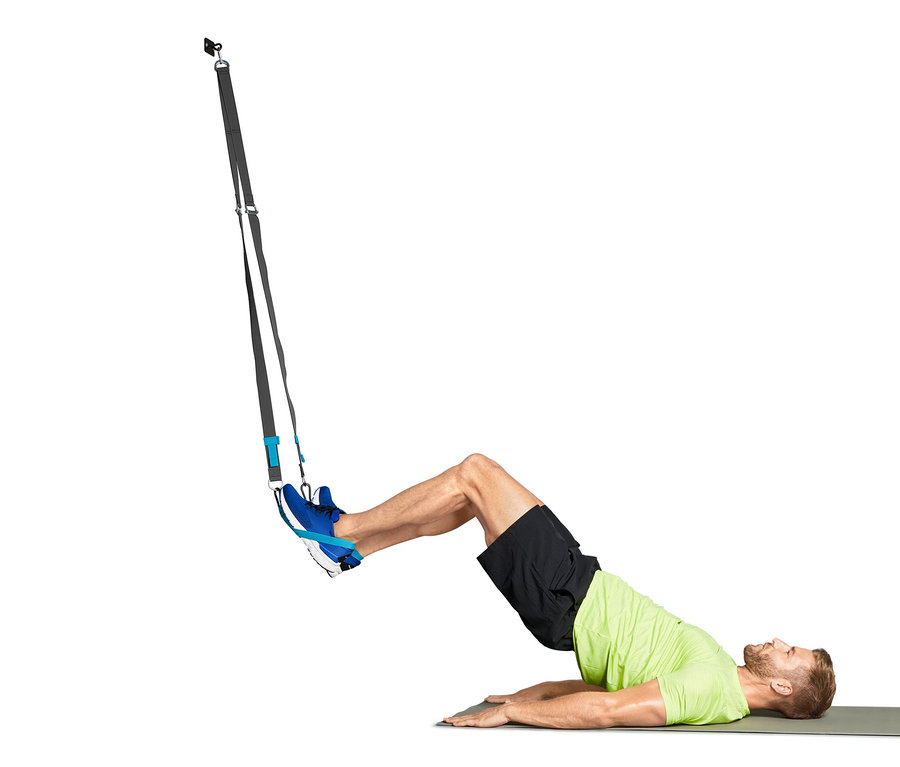 Muž cvičí s závěsným posilovacím systémem na podložce.