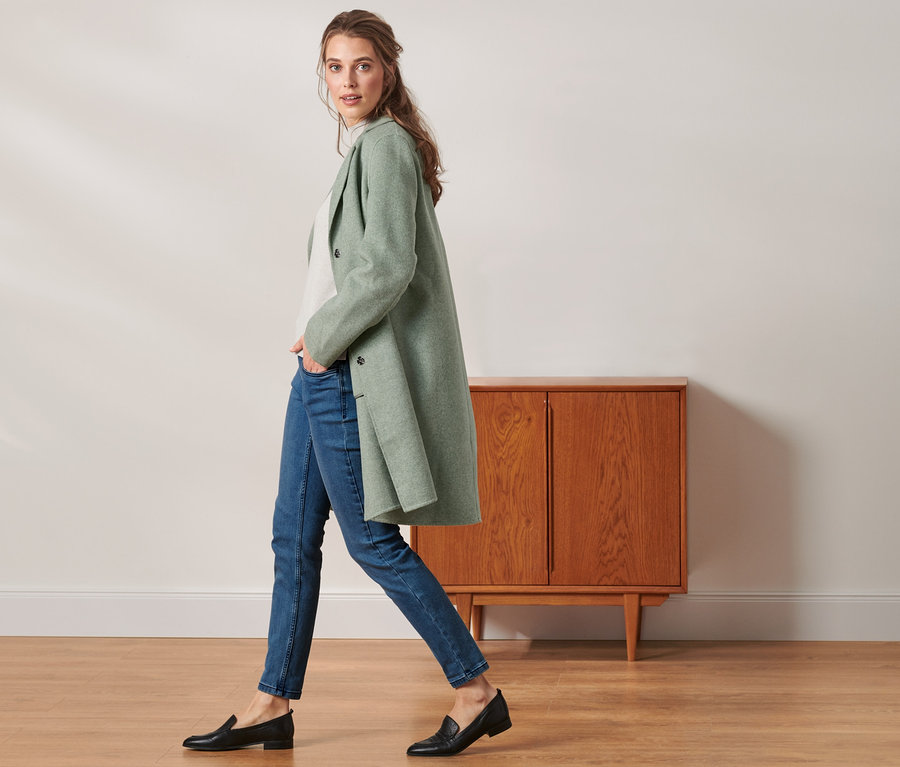 Žena kráčí a má na sobě krátký kabát.