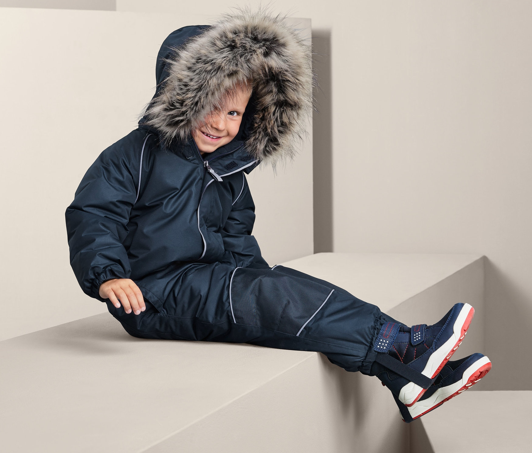 Dítě sedí na bloku v zimní kombinéze.