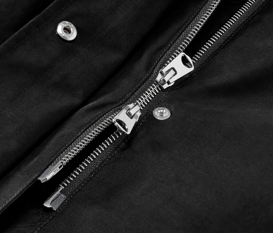 Detail černé parky s kapucí se stříbrným zipem.