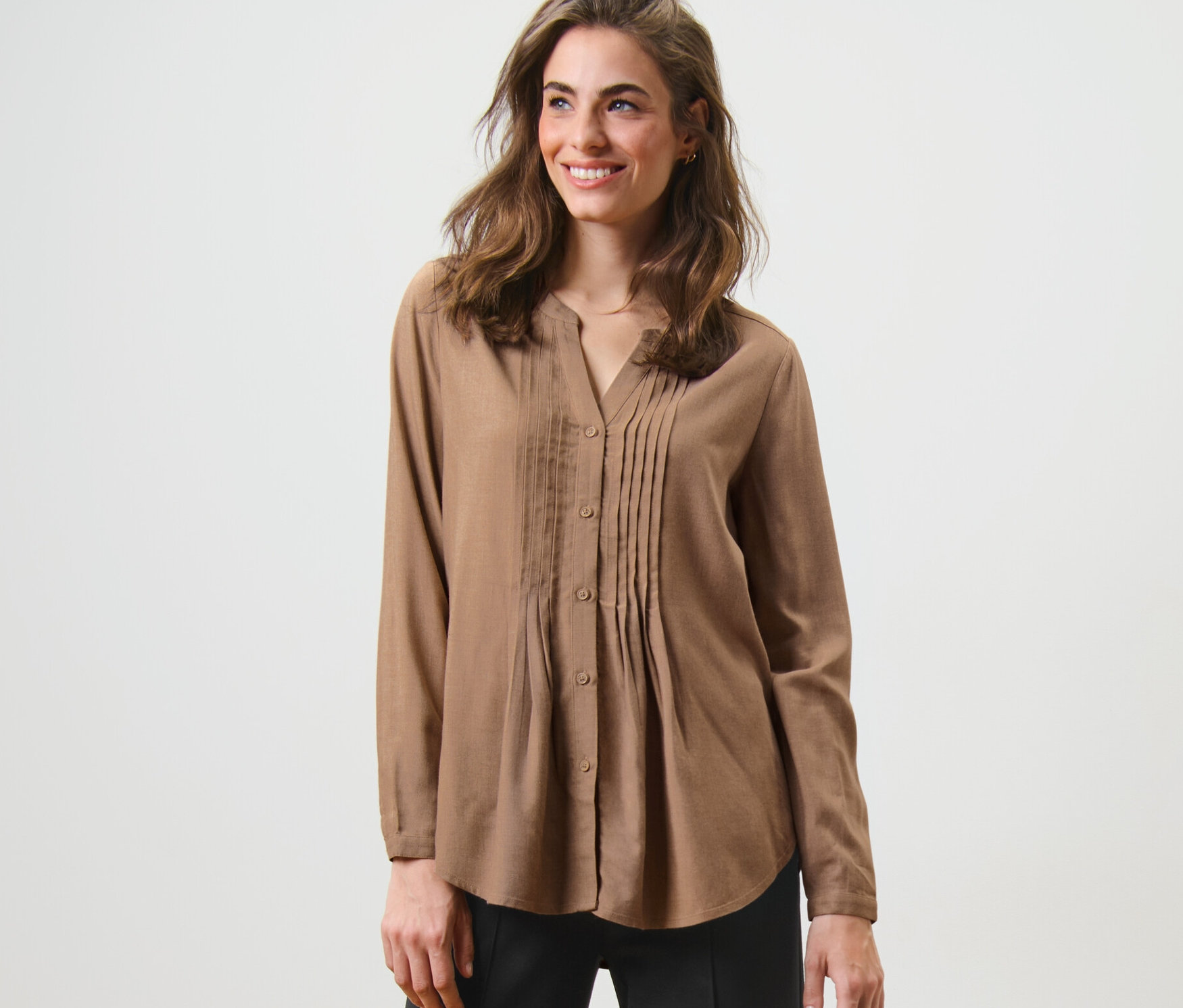 Žena pózuje v tunikové halence.