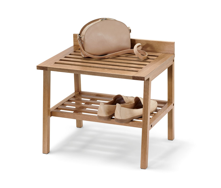 Na horní polici dřevěné stoličky se širokými odkládacími plochami leží kabelka, vespod jsou boty.