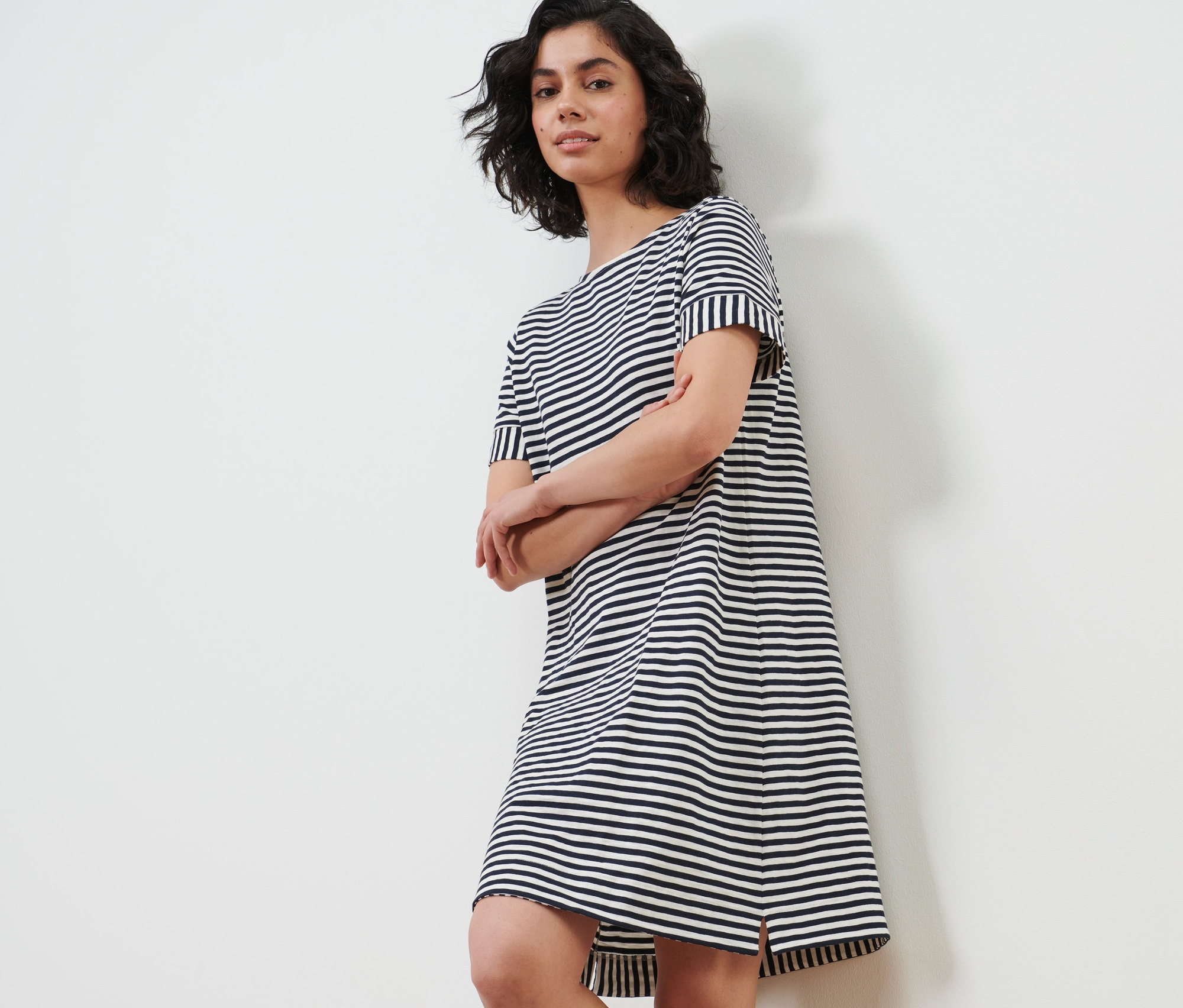 Žena pózuje v proužkovaných žerzejových šatech.