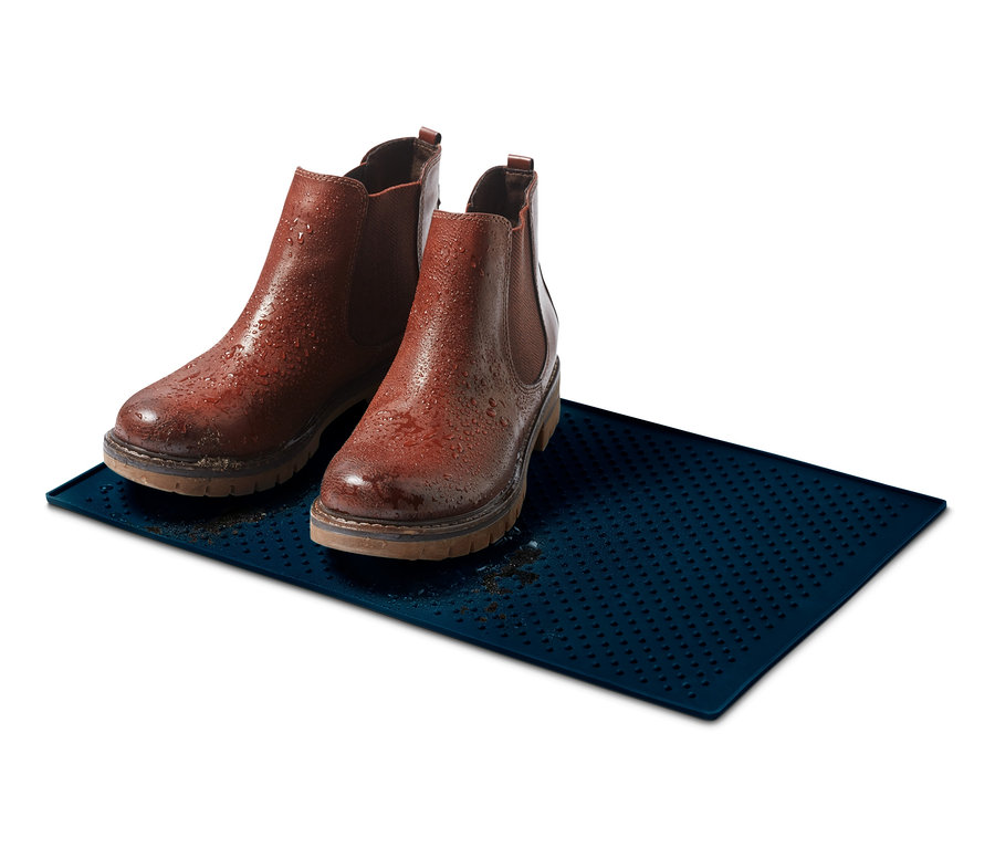 Dva hnědé kožené boty stojí na modré podložce pod misku na krmivo.