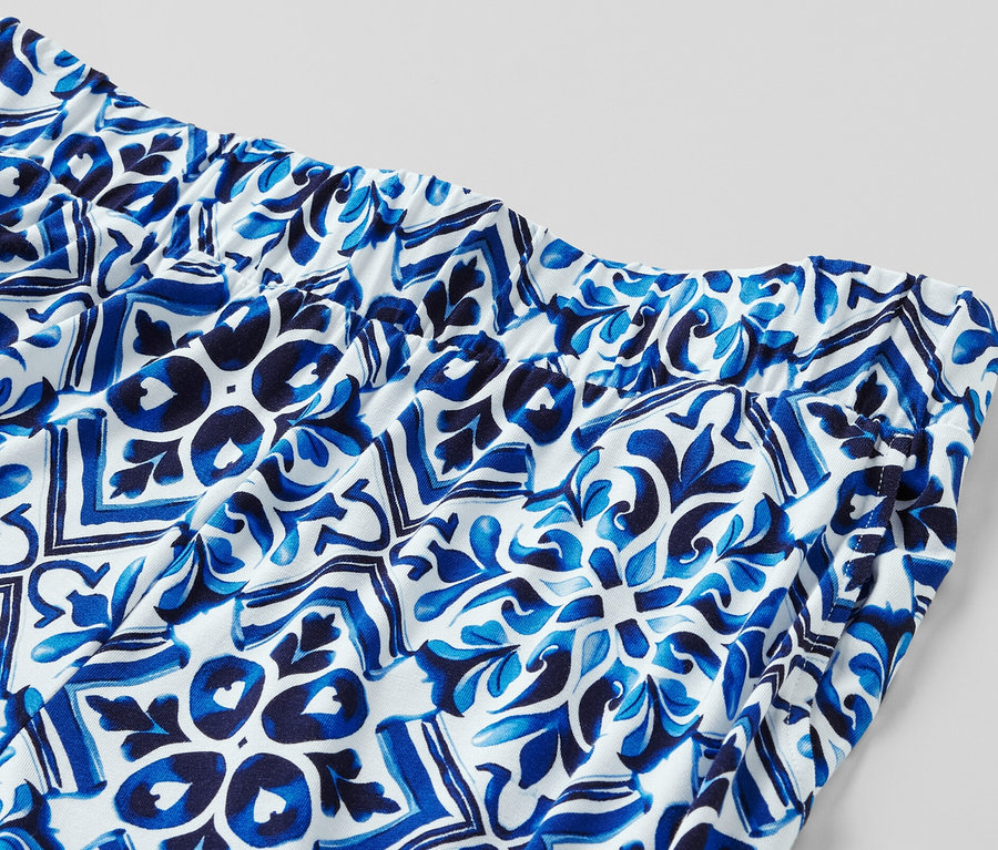 Detail modrých vzorovaných kalhot se širokými nohavicemi s elastickým pasem.