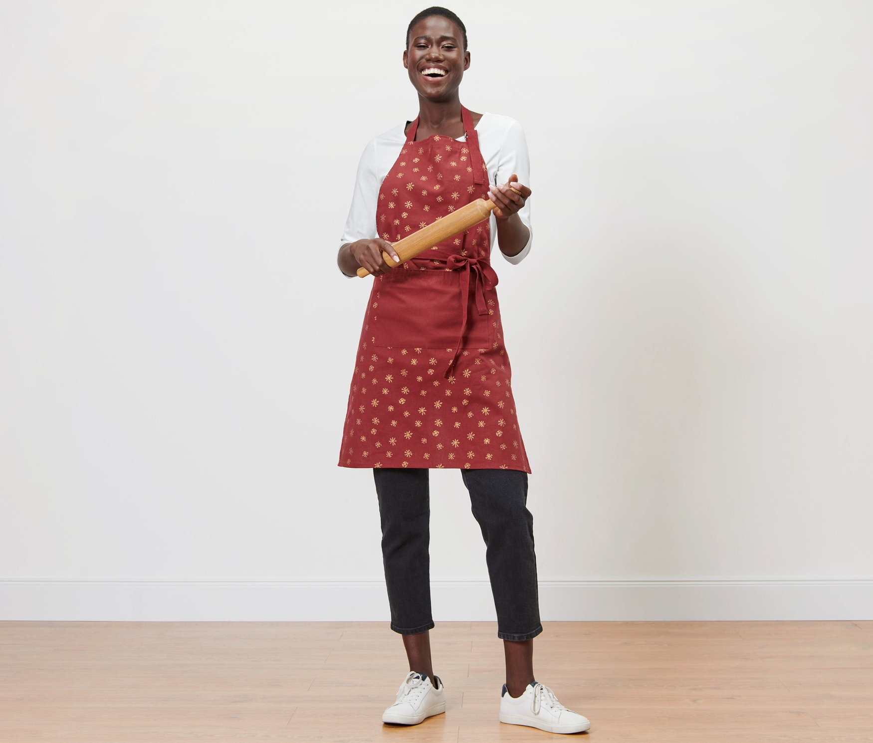 Žena drží váleček na těsto a má na sobě kuchyňskou zástěru.