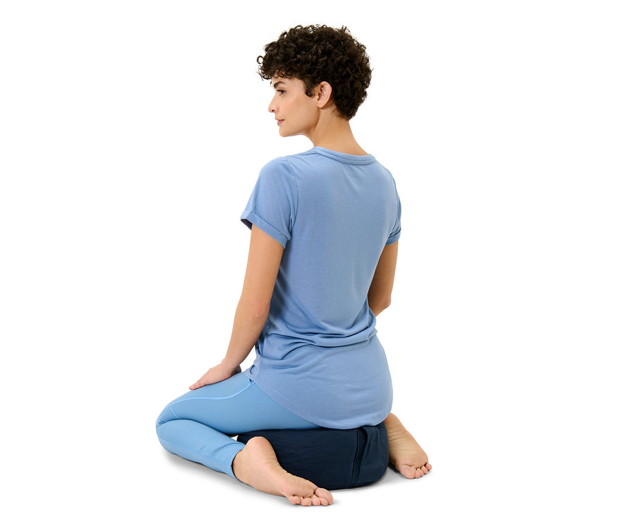 Žena sedí na meditačním polštáři.