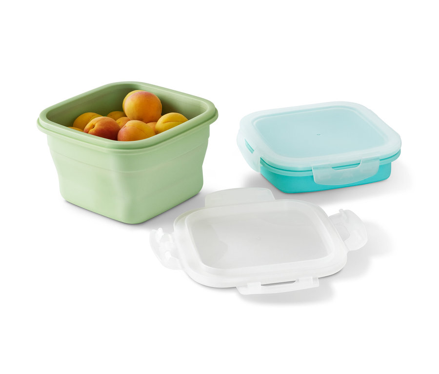 Zelená dóza na potraviny naplněná meruňkami a dvě prázdné dózy na potraviny.