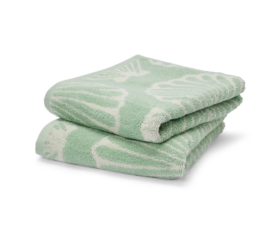Dva zelené ručníky Mušle složené na sobě.