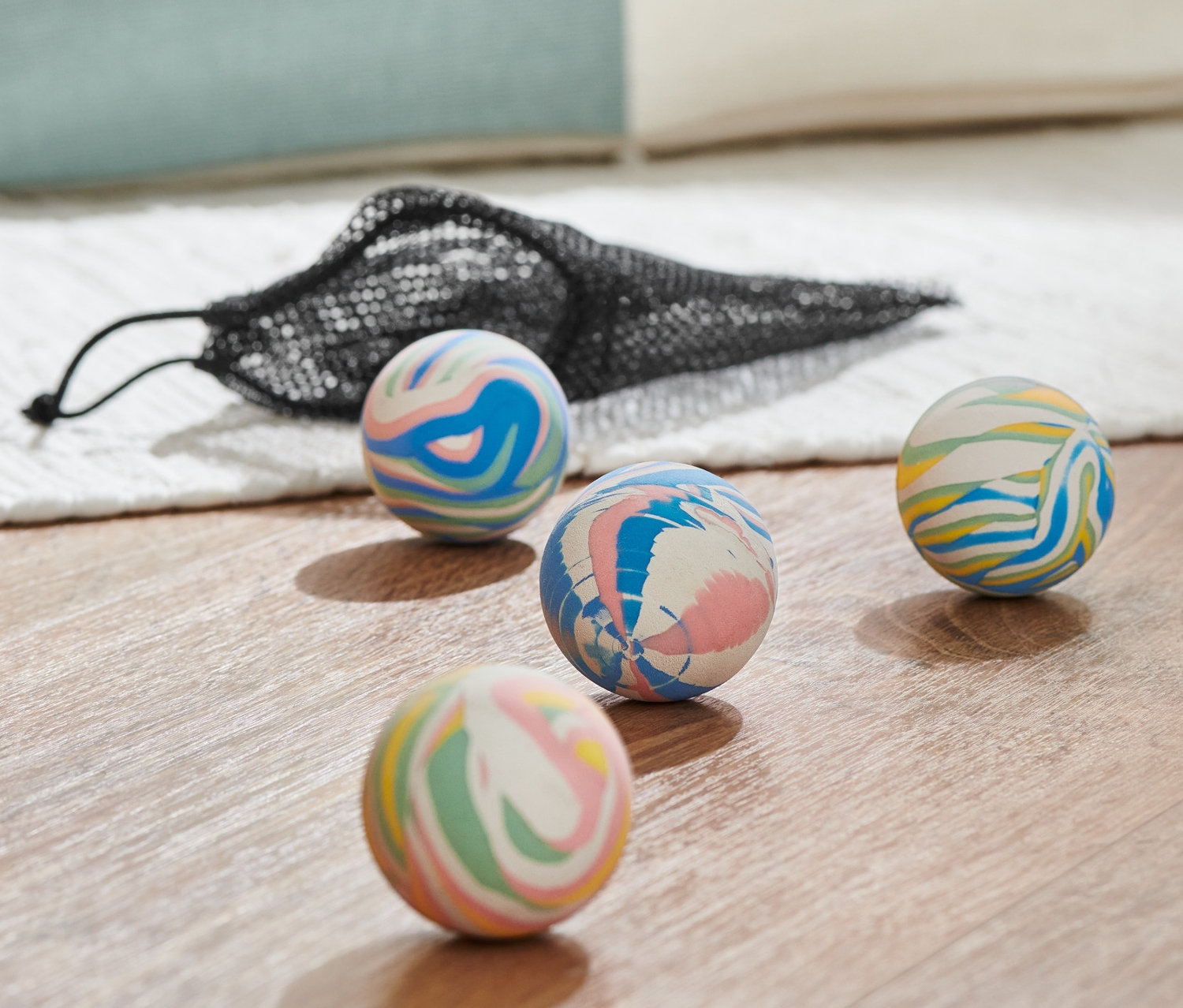 Čtyři vícebarevné hopíky a černá síťovaná taška na dřevěné podlaze.