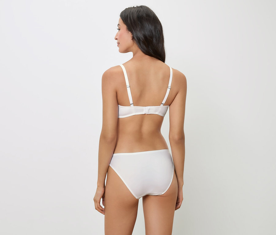 Zezadu pohled na ženu s tmavými vlasy, která má na sobě bílou podprsenku a kalhotky.