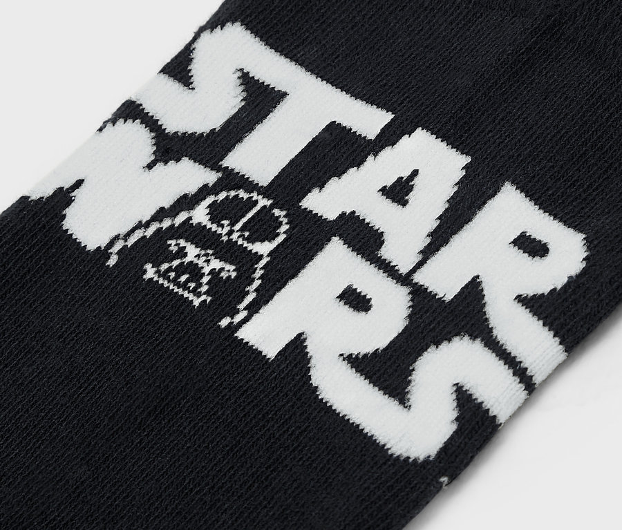 Detail černých ponožek s bílým nápisem STAR WARS a obrázkem Darth Vadera.