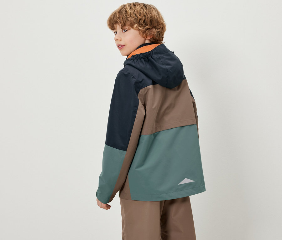 Chlapec se dívá přes rameno a má na sobě barevnou dětskou bundu do každého počasí.