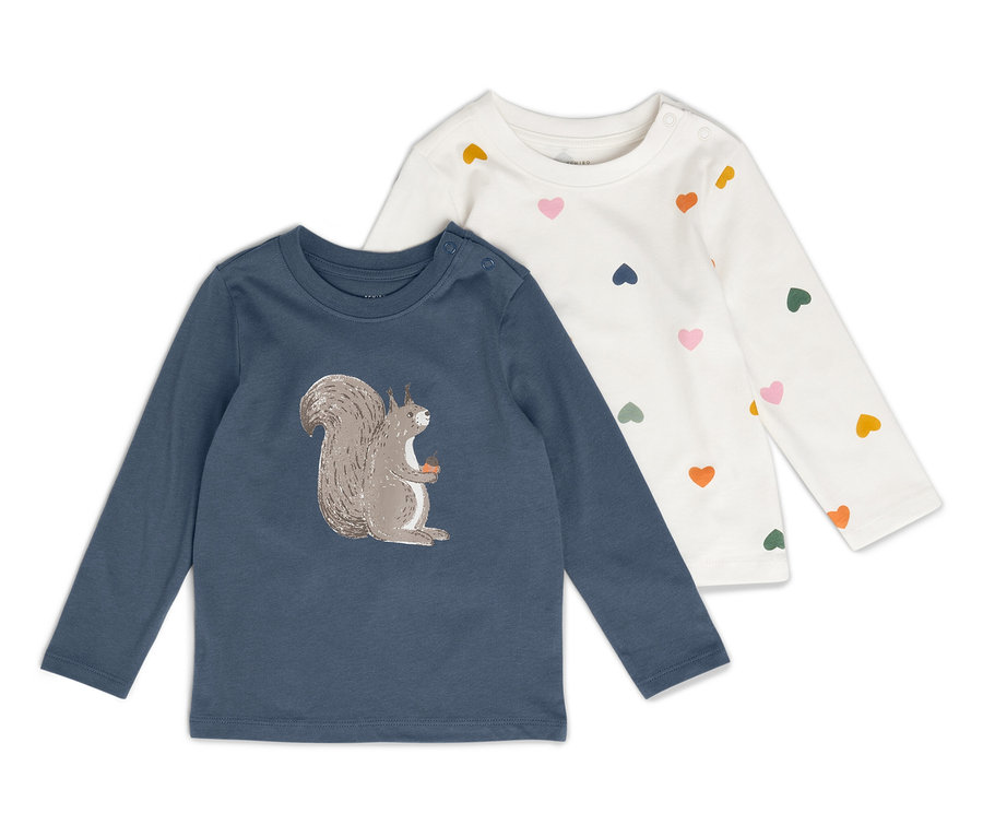 Dvě dětské košile s dlouhým rukávem leží vedle sebe. Jedna košile je modrá s obrázkem veverky, druhá je bílá s barevnými srdíčky.