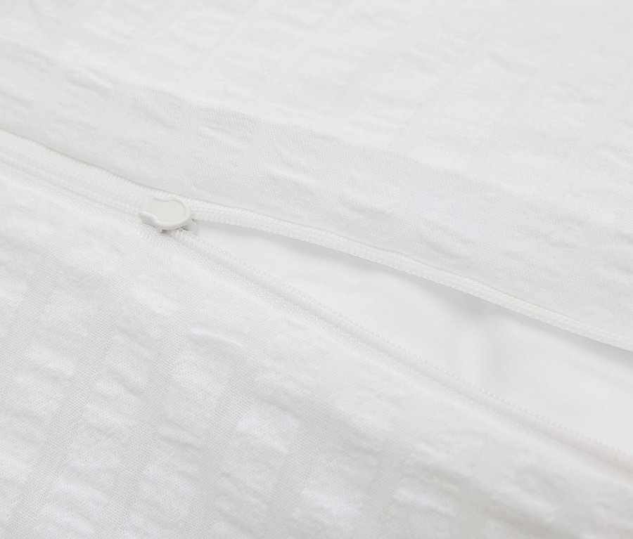 Detail bílého povlečení se zipem.