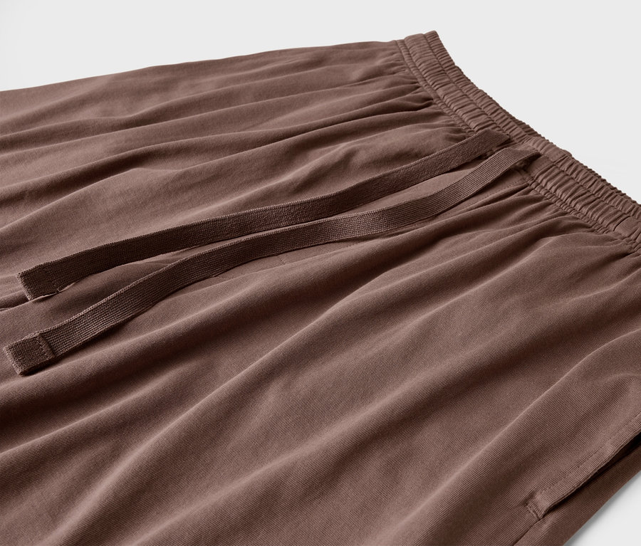 Detail hnědých kalhot se šňůrkou a kapsami.