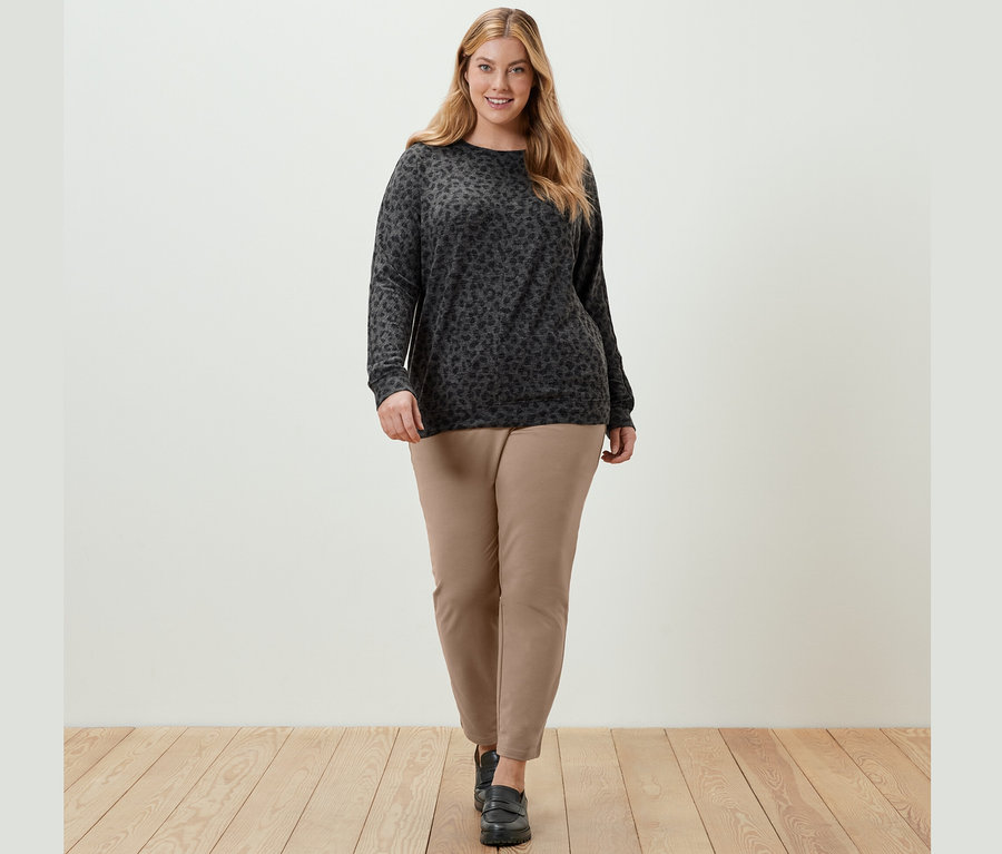 Žena kráčí a má na sobě triko s netopýřími rukávy a potiskem a béžové kalhoty joggpant.