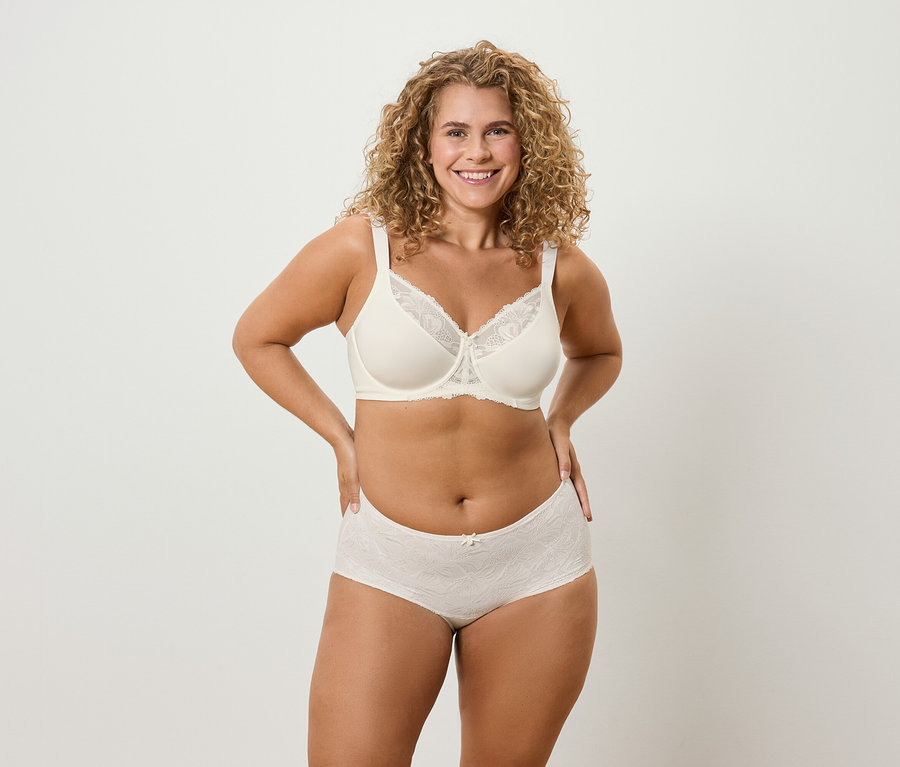 Žena s kudrnatými vlasy pózuje ve spodním prádle.