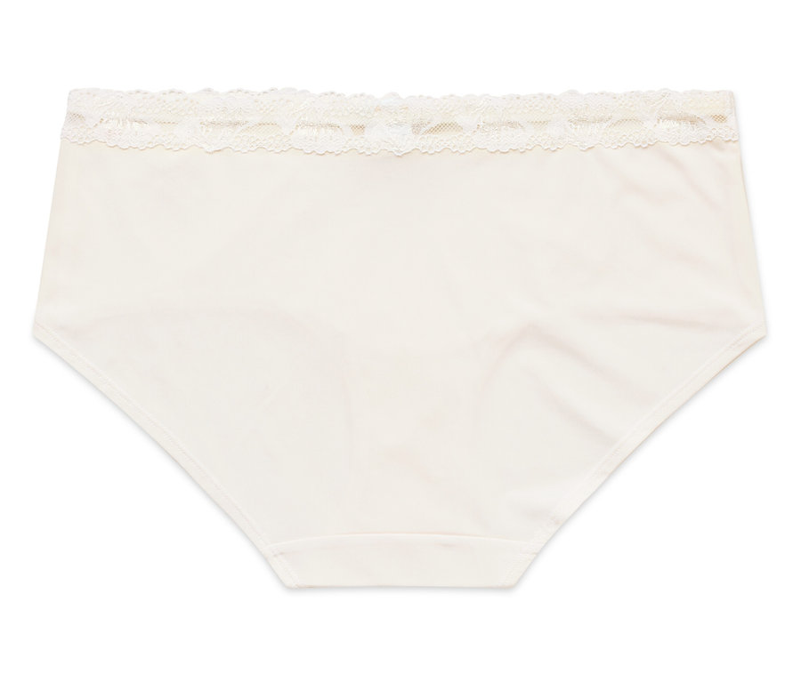 Na bílém pozadí leží krémové dámské kalhotky s krajkovým lemem.
