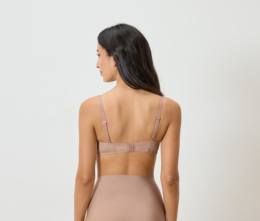 Pohled zezadu na ženu s tmavými vlasy v tělové podprsence a spodním prádle.