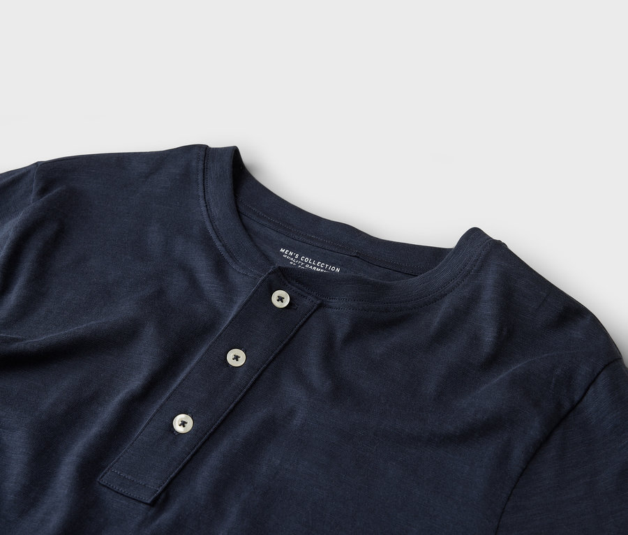 Detailní záběr na tmavě modré tričko Henley se třemi knoflíky.