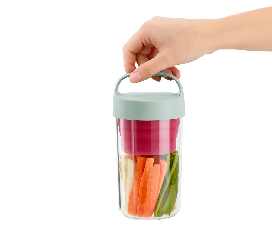 Ruka drží cestovní dózu na oběd naplněnou nakrájenou zeleninou.