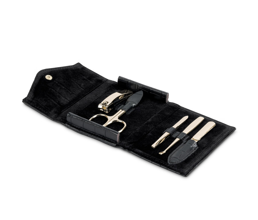 Černá cestovní souprava na manikúru s nůžkami, kleštičkami na nehty a dalšími nástroji.