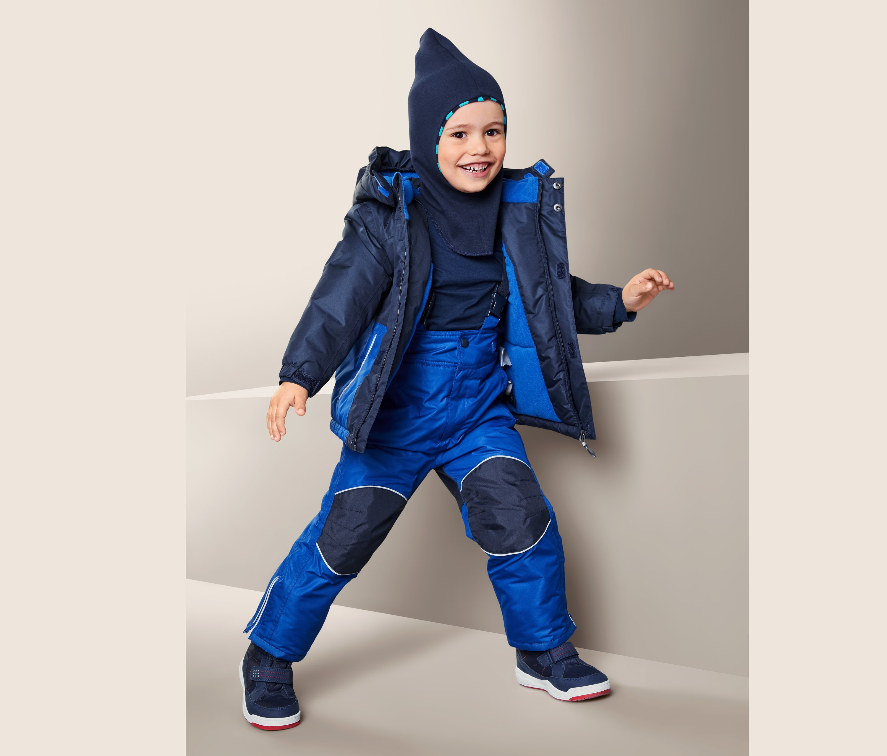 Chlapec má na sobě modrou zimní soupravu.