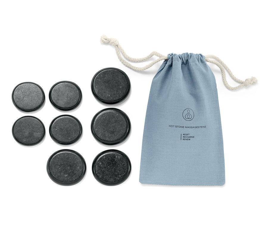 Sada masážních lávových kamenů a modrý látkový obal se stahovací šňůrkou leží na bílém pozadí.
