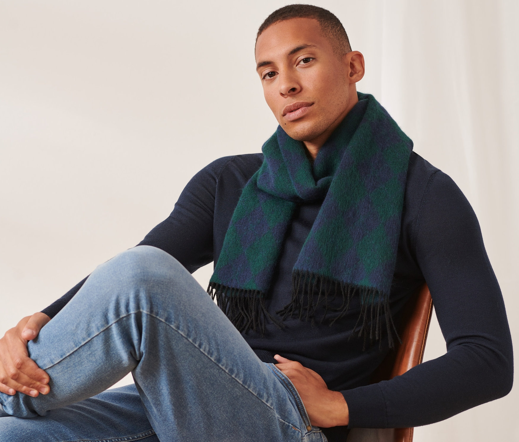 Muž sedí na židli a má na sobě vlněnou šálu.