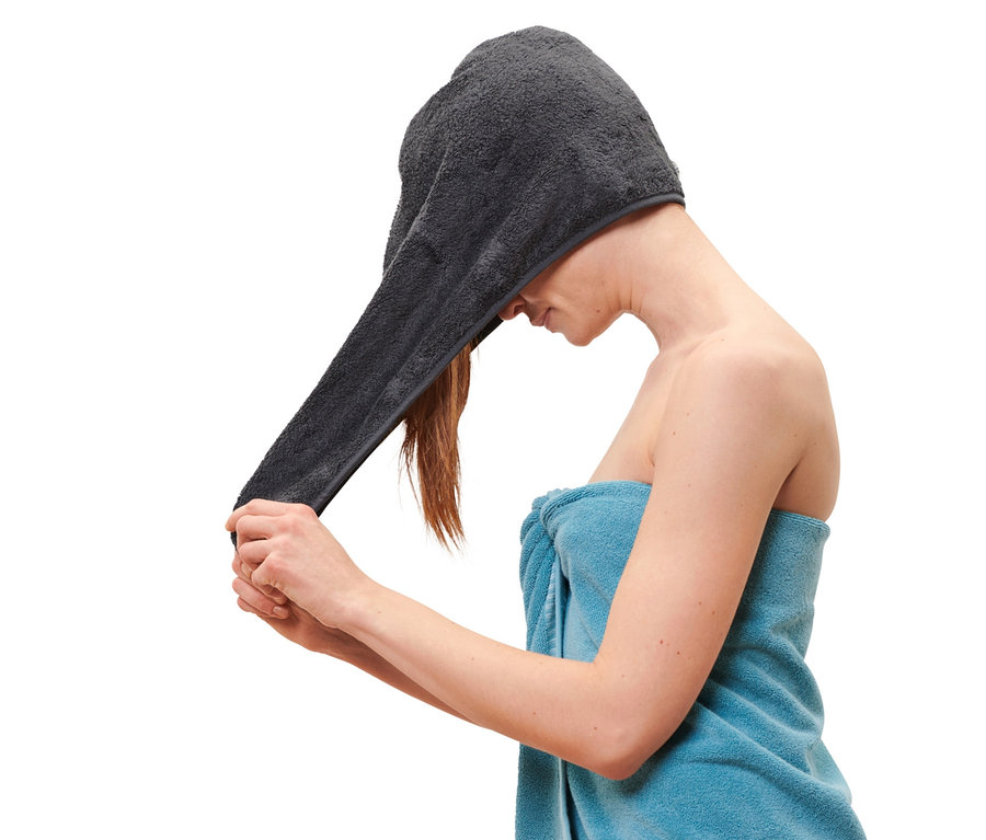Žena si nasazuje na hlavu antracitový ručníkový turban.