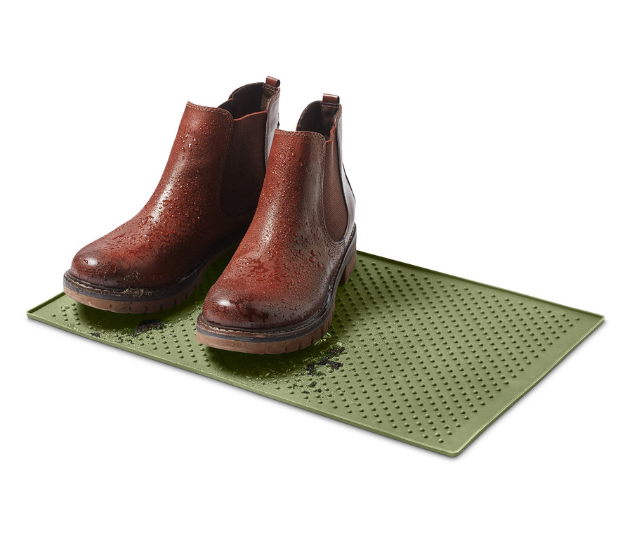 Dvě hnědé boty stojí na zelené podložce pod misku na krmivo.