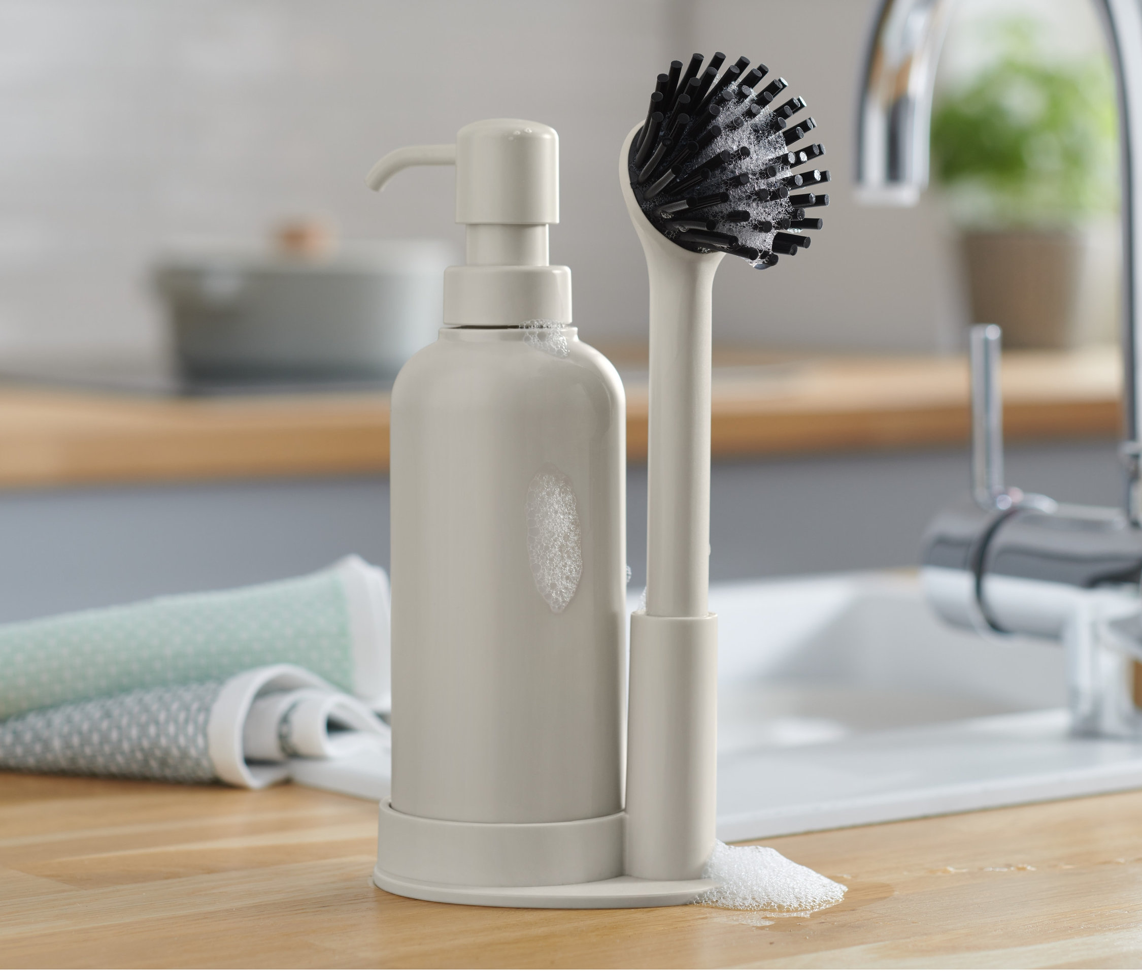 Sada na mytí nádobí s dávkovačem a kartáčem na nádobí na lince.