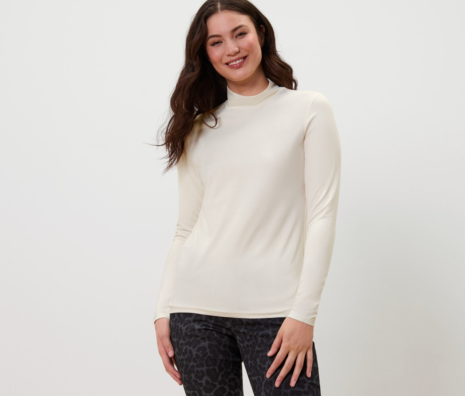 Žena pózuje v halénkovém triku se stojáčkem a vzorovaných kalhotách.