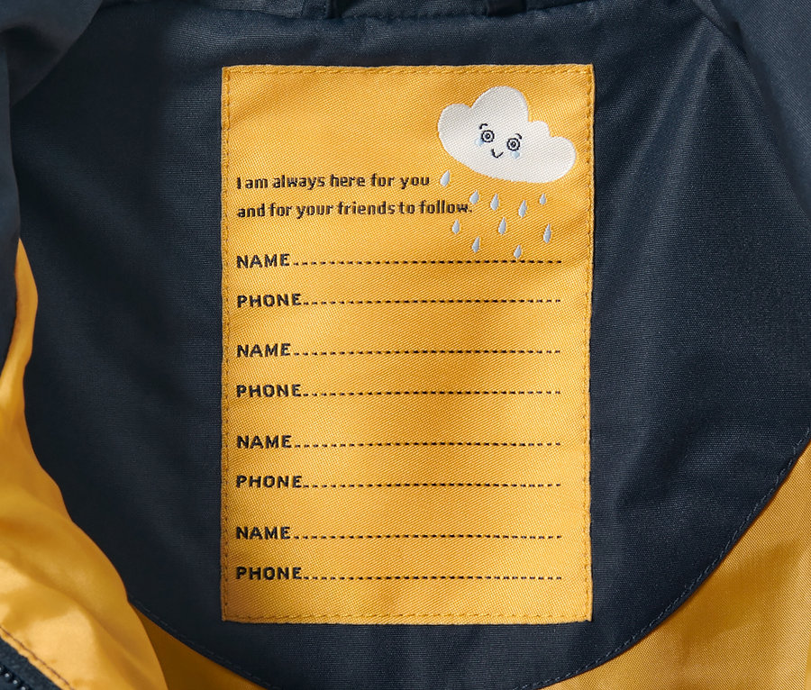 Vnitřek dětské kombinézy do deště s štítkem pro jméno a telefonní číslo.