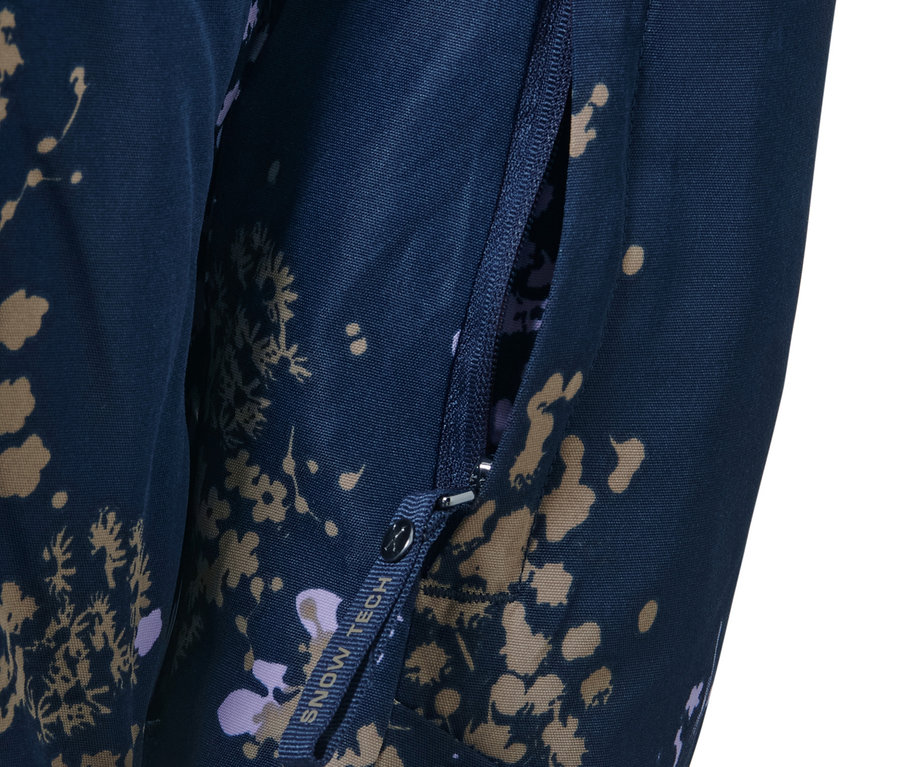 Detail lyžařské bundy s krátkým zipem s otevřenou kapsou na zip.