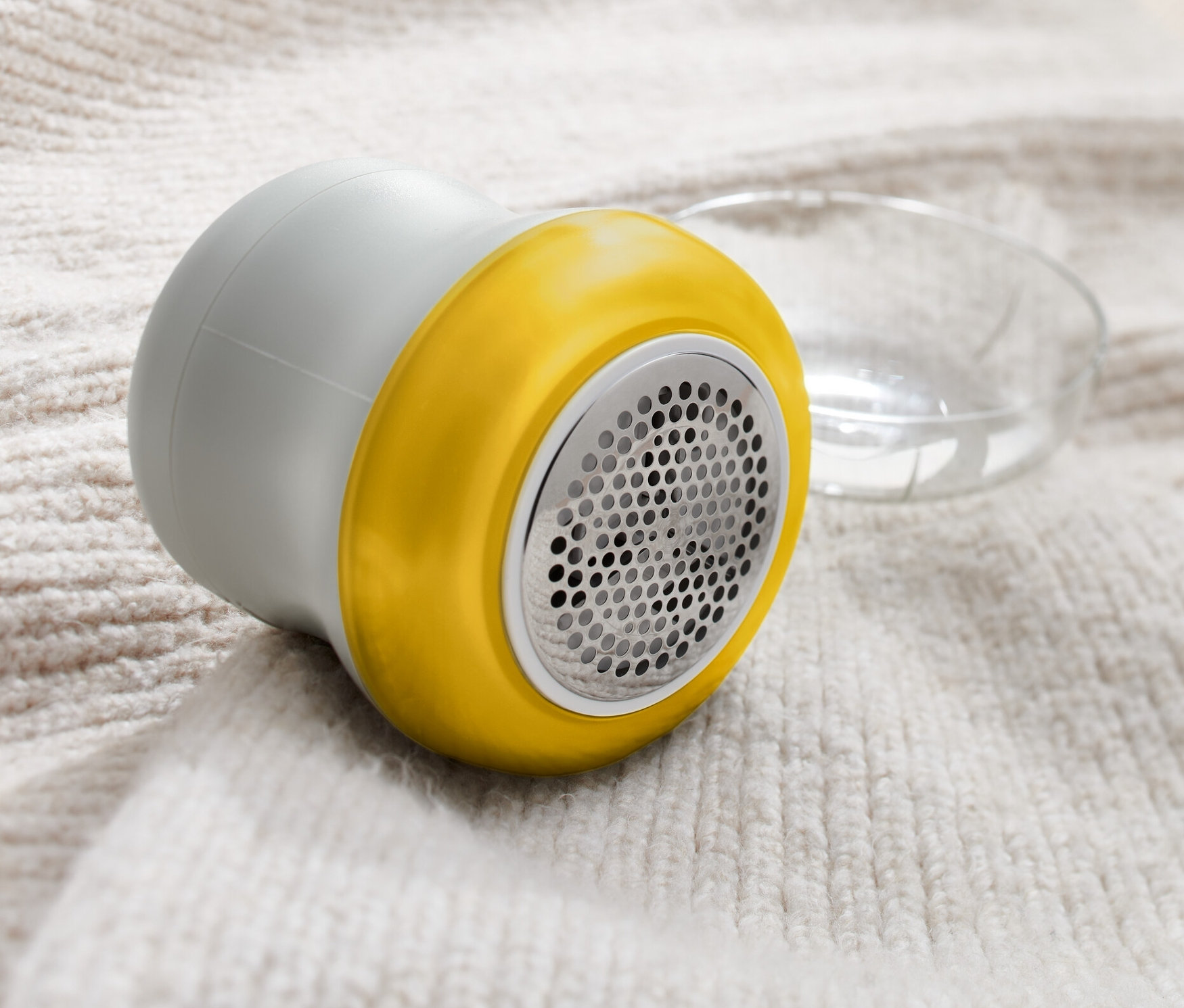 Šedý odstraňovač žmolků leží na svetru.